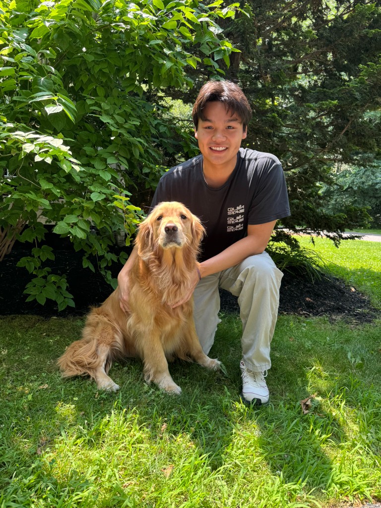 Jeremy kneeling outdoors with his golden retriever